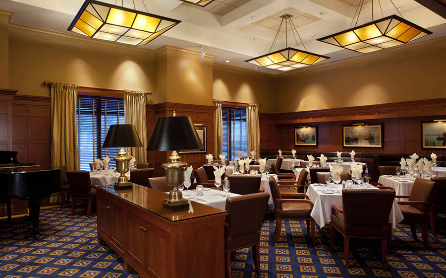 dark paneled dining room with white linens and artwork